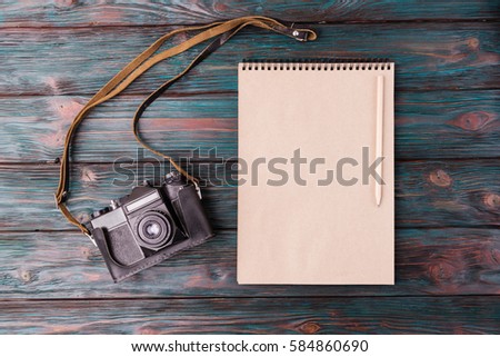 Flat lay of blank note pad and retro camera