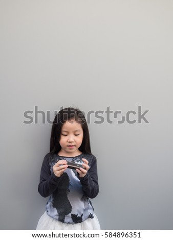 Little asian child play the harmonica, gray background