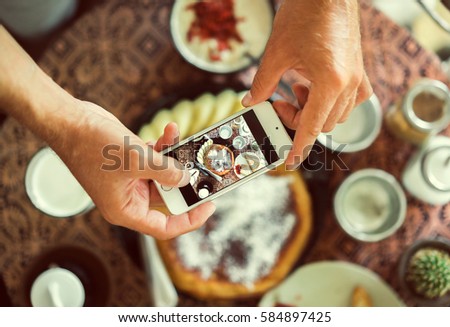 man using smartphone in cafe. smartphone white screen. hand holding smartphone. Hands with the phone close-up pictures of food. Pancake, cereal and coffee for breakfast. vintage tone.