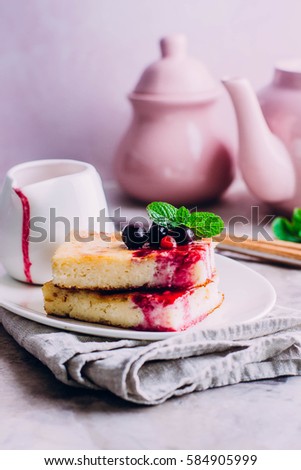 Homemade Cottage cheese casserole pieces with berry sauce decorated berry and mint on gray table background. Summer cake or pie. Healthy food concept. Copy space