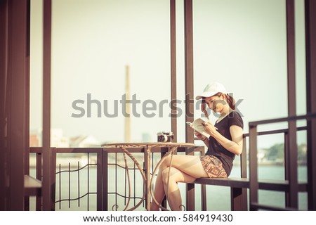 Stylish student girl relax with book on river side in Thailand. Outdoor lifestyle picture