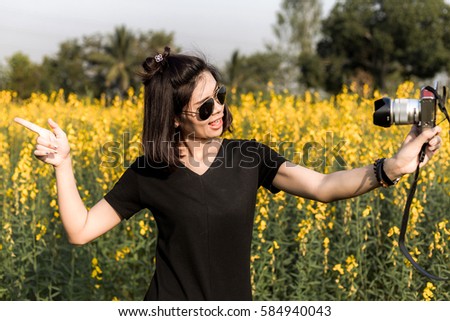 Beautiful Asian girl taking pictures on the flowers field