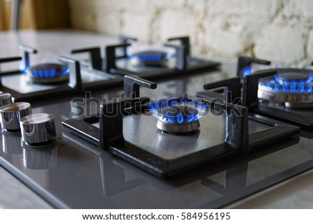 Cooktop with burning gas ring. Gas cooker with blue flames. Tinted photo. Royalty-Free Stock Photo #584956195