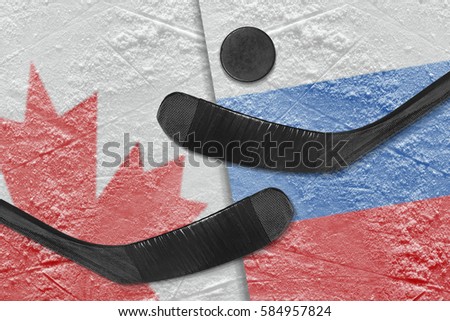 Hockey puck, hockey sticks and a picture of the Canadian and the Russian flag on the ice. Concept