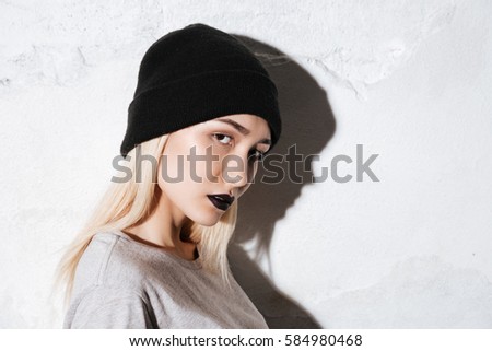 Side view of Young Hipster in black hat looking at camera