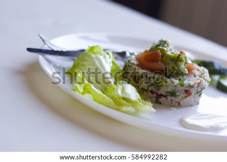 Rice salad roll with cucumber slices, tomatoes, salad leaves and broccoli on a white background.