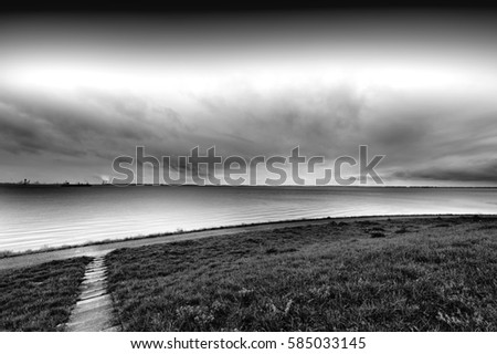 Dunes and sea at the North Sea shore in Holland. Dutch landscape with dike protects against flooding. Black and white picture