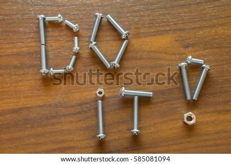 The lettering "Do it!" consisting of screws on a wooden table