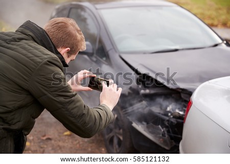 Man Taking Photo Of Car Accident On Mobile Phone