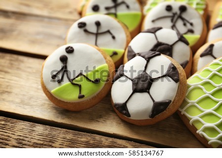 Creative cookies decorated in football style on wooden background, closeup