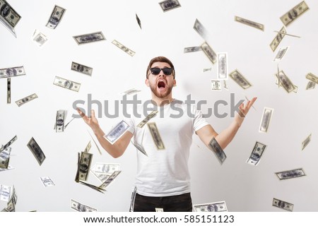 young happy man with a beard in white shirt standing under money