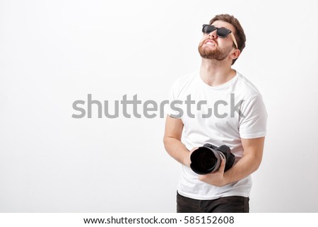 young professional photographer in shirt holds heavy digital cam