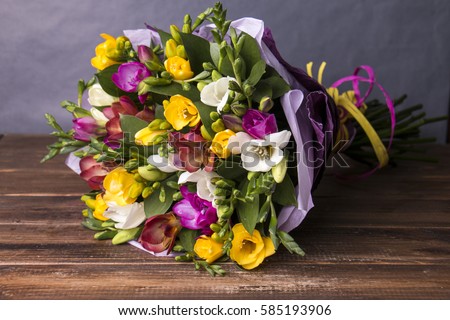 Bouquet of colorful fresh freesia on a wooden background Royalty-Free Stock Photo #585193906