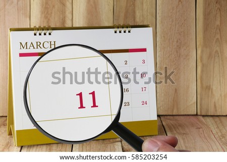 Magnifying glass in hand on calendar you can look eleven day of month,Focus number eleven in March,Concept in business and meetings.