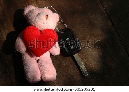 Pink teddy bear red Heart of love and key on background wooden.