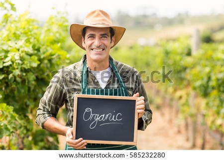 Portrait of a smiling farmer holding an organic sign
