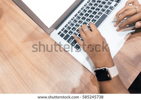 Hands of woman wearing smartwatch on the keyboard of her laptop computer. Female working on laptop in a cafe.