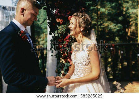 Bride holds groom's hand standing before wedding altar