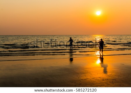 silhouette people honeymoon romantic couple in love walking on the beach on orange sunset background.