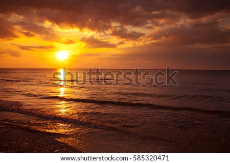 the sunset in the backdrop of the ocean , the bright sun in the evening at sunset , seascape , warm evening on the sea