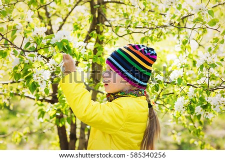 portrait beautiful little girl, with bush blossoming apple-tree, smiles