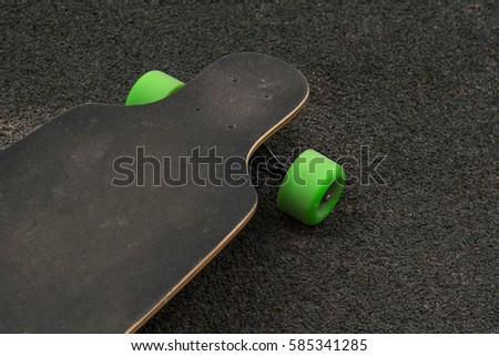 Old used skateboard isolated on the ground. Old style longboard. Black skateboard on an empty asphalt road. Shallow depth of field.