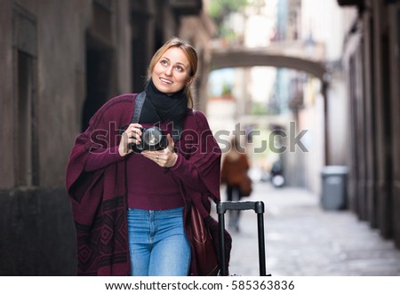 Young  happy woman looking curious and taking pictures outdoors