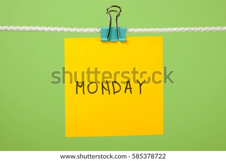 Yellow paper sheet on the string with text Monday over colorful background