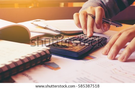 Woman using calculator with doing finance at home office. Royalty-Free Stock Photo #585387518