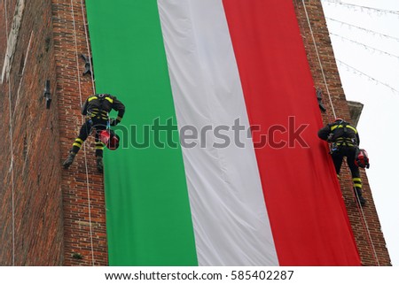 Italian very brave fearless firefighters climb the old tower with a big Italian flag
