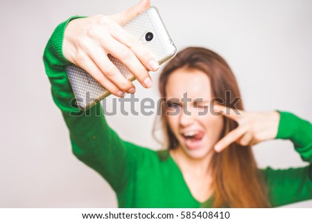Woman shows tongue and peace symbol doing selfi,sell phone in focus