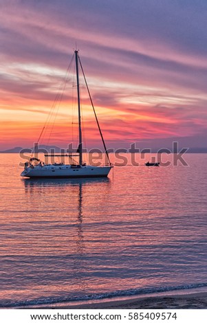Sailboat sunset silhouette is a sailboat sailing along the water with a colorful purple and pink night sky in the background