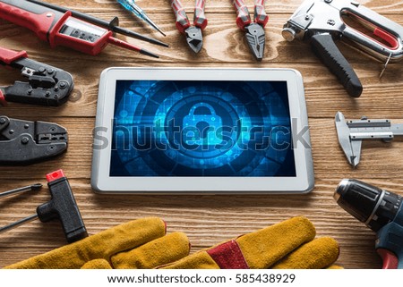 Tablet pc with security concept on screen and industrial tools around