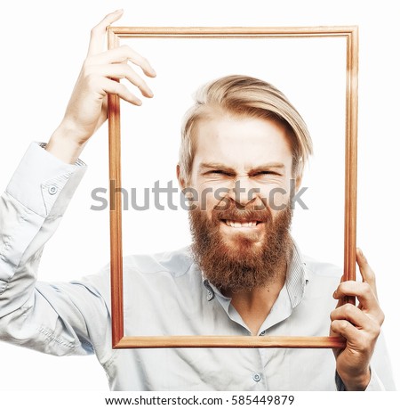 Funny picture. Young man wearing beard holding picture frame in front of his face and fun hamming, isolated on white.