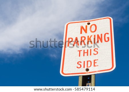 "No Parking this Side" sign with brilliant blue skies and clouds in background. 