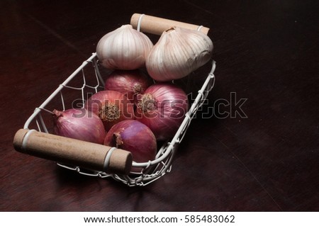 Onions and garlic in basket with dark wood background
