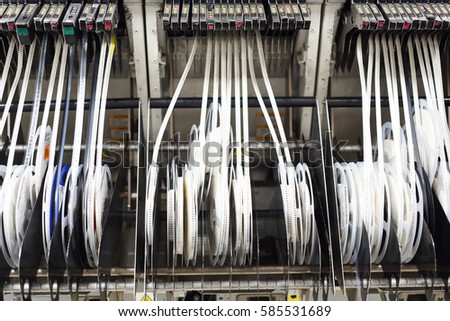 Reels in chip shooter machine at SMT line used simple package components such as resistors and capacitors for surface mounting at electronic manufacturing factories.  Royalty-Free Stock Photo #585531689