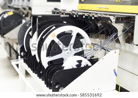 Reels in pick and place chip shooter machine at SMT line used simple package components such as resistors and capacitors for surface mounting at electronic manufacturing factories.  Royalty-Free Stock Photo #585531692