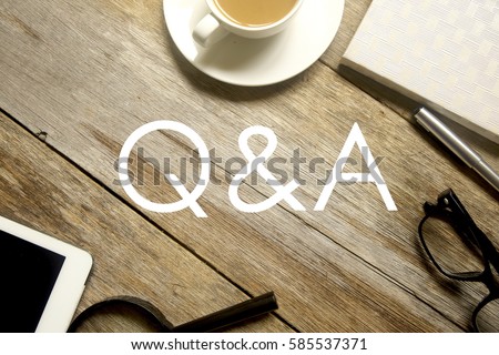 Business concept. Top view of tablet pc, magnifying glass, pen, notebook, glasses and a cup of coffee with Q&A written on wooden table. Royalty-Free Stock Photo #585537371