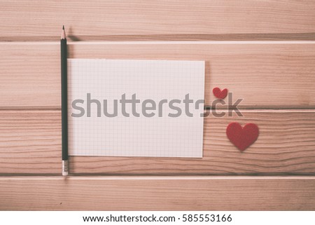Red heart and pencil with blank paper on wood background. vintage retro color style.