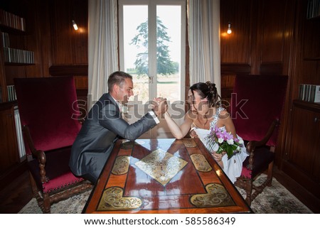 young married couple make an arm wrestling after the ceremony of marriage