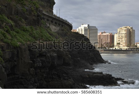Puerto de la Cruz with hotels and beach in background and rocky seashore in foreground, picture from Tenerife Spain.