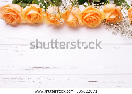 Frame or border  from peach color roses flowers on white wooden background. Shabby chic. Place for text.Selective focus.Top view.
