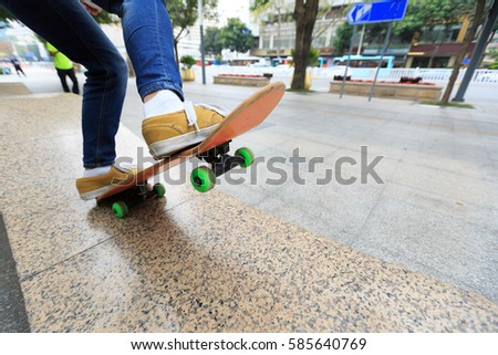 young skateboarder legs riding skateboard at city skatepark