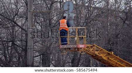 Installation of a road sign on a column. The worker establishes a sign of traffic standing on the elevator