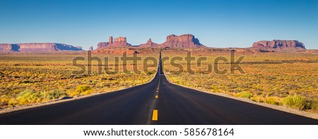 Classic panorama view of historic U.S. Route 163 running through famous Monument Valley in beautiful golden evening light at sunset on a beautiful sunny day with blue sky in summer, Utah, USA Royalty-Free Stock Photo #585678164