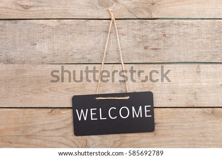 Blackboards with inscription "Welcome" on wooden background Royalty-Free Stock Photo #585692789