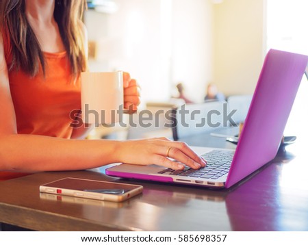 Pretty Young woman using laptop computer. Female working on laptop in an outdoor cafe.