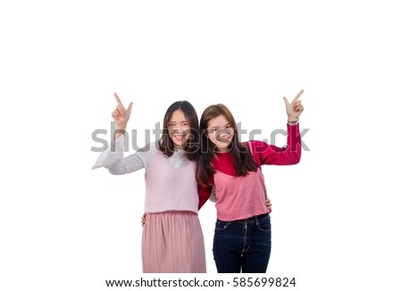 Two girls point her fingers at other side of blank space.