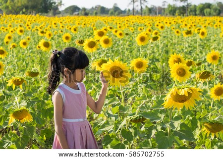 Beautiful child with sunflower in spring field